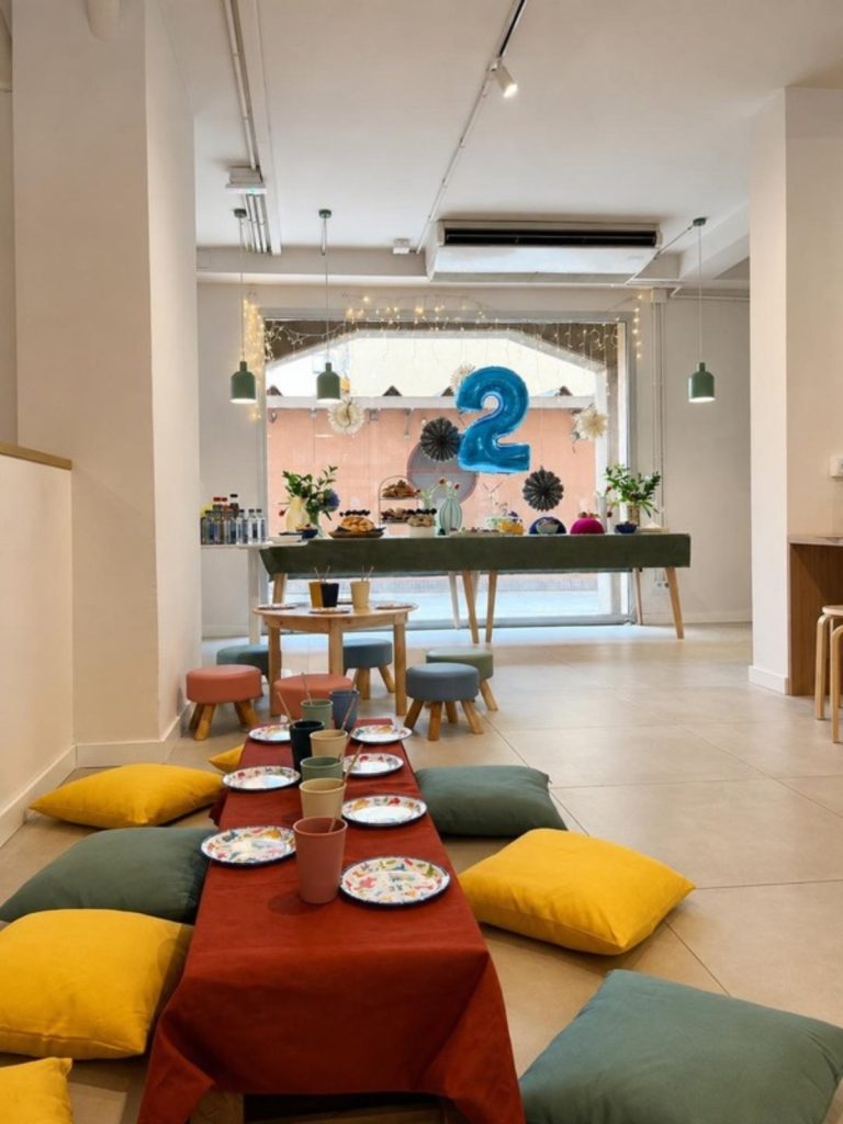 Sala preparada per a una festa d'aniversari infantil amb taula baixa i coixins de colors
